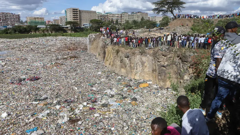 epa11474629 Onlookers watch as bodies wrapped in bags are being retrieved from inside a quarry turned into a dump site at Embakasi area in Nairobi, Kenya, 12 July 2024. Police stated that six severely mutilated female bodies, in various stages of decomposition and wrapped in nylon bags and ropes, were recovered from the former quarry near Mukuru Kwa Njenga slum in Nairobi. Police said the area has been declared a crime scene and an investigation is underway. EPA/STRINGER