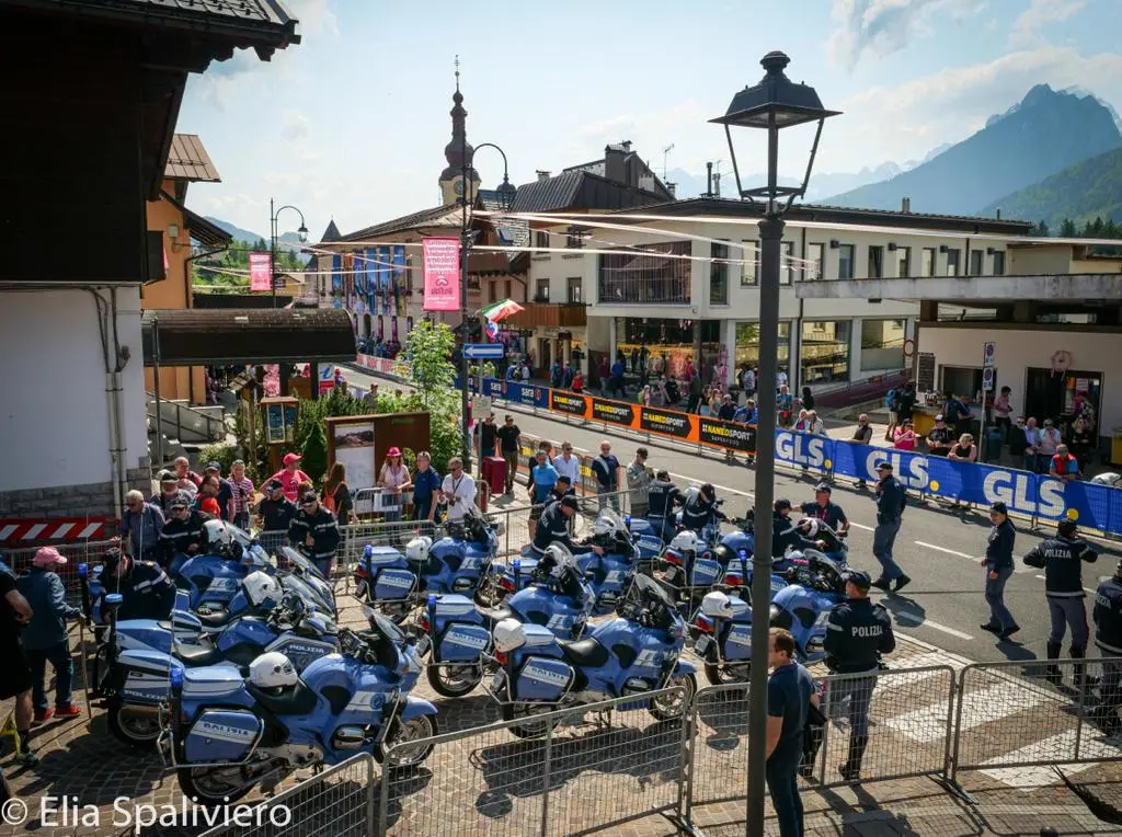 Splende il sole, intanto, in Friuli. Finalmente bel tempo sul Giro inseguito per giorni e giorni dalla pioggia nella sua risalita al Nord; spettacolo fino all’ultimo per una classifica apertissima come non mai. Tantissime le persone sulle strade, a Tarvisio e al Santuario, che applaudono i ciclisti ma soprattutto i due atleti friulani in gara, Alessandro De Marchi e Jonathan Milan, con la sua maglia ciclamino semplicemente passato in 21 tappe da esordiente a eroe acclamato da tutti e protagonista ieri dell’impresa del Giro arrivando in tempo massimo dopo una notte insonne. E poi turisti-tifosi in arrivo da Austria, soprattutto Slovenia per il loro Roglic; telespettatori incollati alle tv da tutto il mondo per assistere al debutto della misteriosa salita del Lussari, musica per le orecchie della Regione (Foto Petrussi)