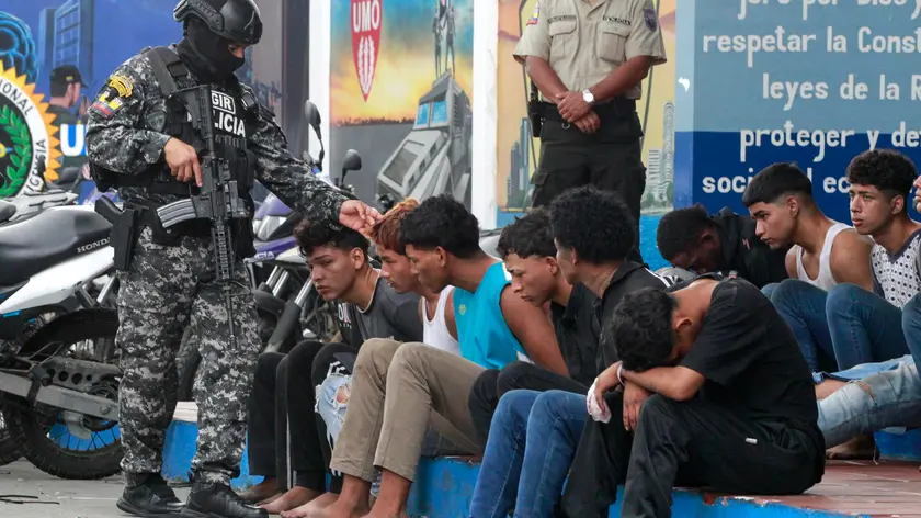 epa11067977 A police officer guards the detainees of an armed group for the temporary takeover of a television channel, in Guayaquil, Ecuador, 10 January 2024. The country is experiencing moments of great tension after the raid by an armed commando on TC Television in Guayaquil, which ended with the arrest of thirteen men and the release of the channel's staff. Ecuador is in a state of emergency for sixty days, which includes a curfew during the night and early morning, due to a series of incidents in prisons, which broke out on 08 January, and the ‘alleged escape’ of one of the most dangerous criminals from the country. Noboa declared on 09 January that government forces were engaged in an 'internal armed conflict' with armed criminal gangs, allowing him to use the Army and not just the Police to counter the violence. EPA/CARLOS DURAN ARAUJO