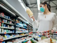 Young person with protective face mask buying groceries/supplies in the supermarket.Preparation for a pandemic quarantine due to coronavirus covid-19 outbreak.Choosing nonperishable food essentials