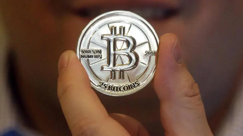 FILE - In this April 3, 2013 file photo, Mike Caldwell, a 35-year-old software engineer, holds a 25 Bitcoin token at his shop in Sandy, Utah. As Venezuelas national currency loses value at a catastrophic rate, thousands have begun turning to the world of cryptocurrency to salvage what little value remains from their increasingly worthless bolivars. (ANSA/AP Photo/Rick Bowmer, File) [CopyrightNotice: Copyright 2017 The Associated Press. All rights reserved.]
