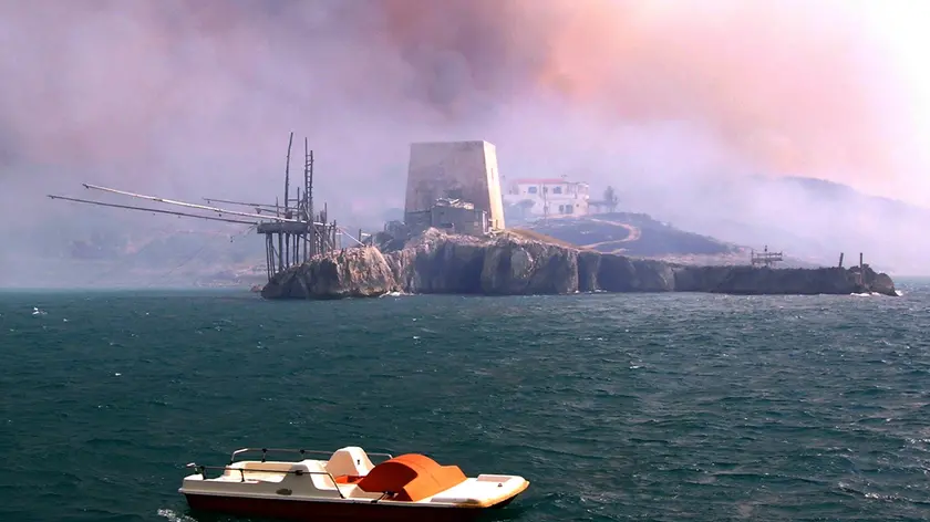 20070724 - PESCHICI (FOGGIA) - CRO : INCENDI: PUGLIA; CENTINAIA GLI ETTARI DISTRUTTI SUL GARGANO. Un pattino in mare a largo di Peschici, con il cielo coperto dal fumo degli incendi. ANSA / NICOLA LANESE / PAL
