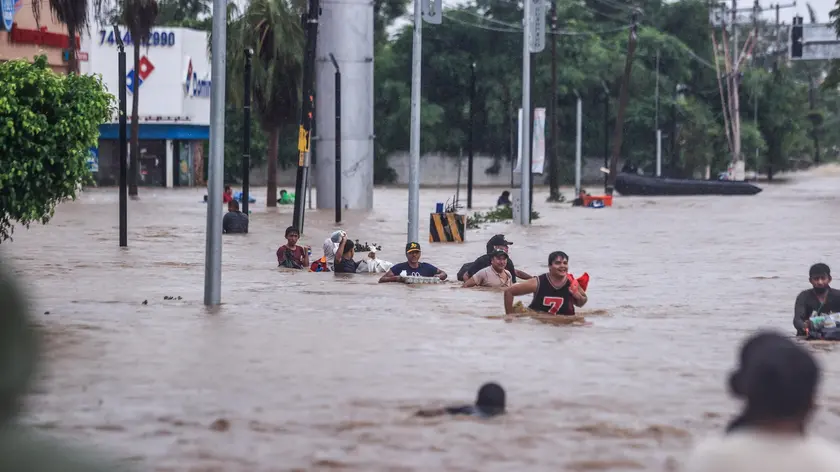 epaselect epa11629594 People cross an avenue flooded by the passage of Hurricane John in the upper part of the port of Acapulco, in Guerrero, Mexico, 27 September 2024. Mexican authorities reported another six deaths from Hurricane John, bringing the death toll to 22 since the cyclone's impact, of which 18 are in the southern state of Guerrero, another three in neighboring Oaxaca, and one more in Michoacan. EPA/DAVID GUZMAN