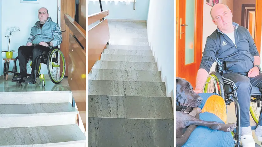 Massimo Pavan sul pianerottolo del suo appartamento, davanti alla rampa di scale che gli impedisce di uscire di casa. E, a destra con il suo fedele cucciolo di alano che gli tiene compagnia