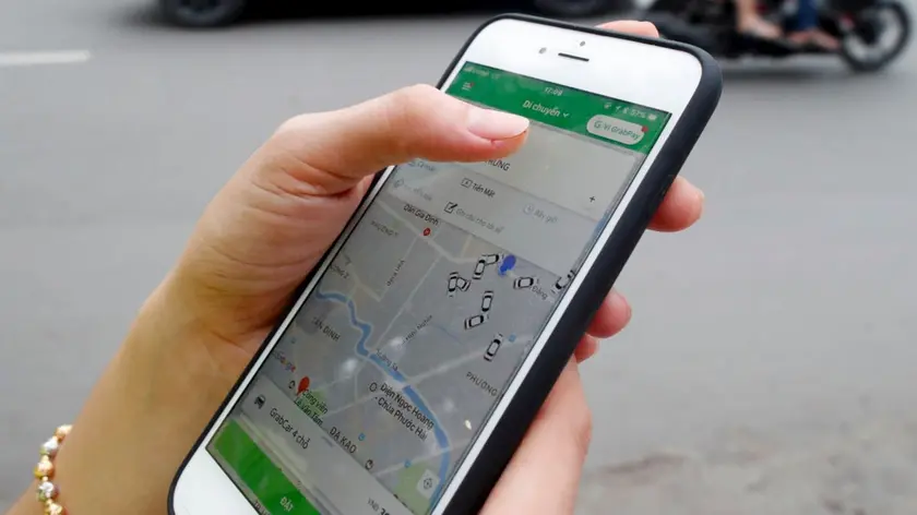 Woman using the Grab app on an Apple iPhone 6 Ho Chi Minh City. Vietnam.