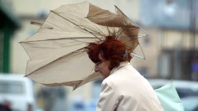 Una donna regge l'ombrello durant ele forti raffiche di bora a Trieste. ANDREA LASORTE