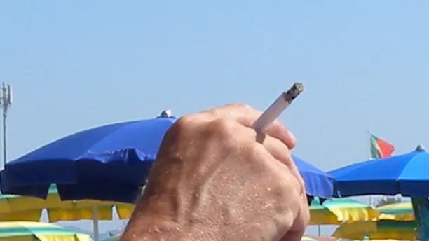 Un ragazzo fuma una sigaretta sulla spiaggia in una foto d'archivio. ANSA/FRANCO SILVI