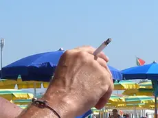 Un ragazzo fuma una sigaretta sulla spiaggia in una foto d'archivio. ANSA/FRANCO SILVI