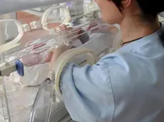 Una infermiera guarda un neonato in ospedale ANSA