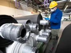 Un operaio dotato di guanti, occhiali protettivi e mascherina, a lavoro nell'impianto produttivo di Alcantara, uno dei brand pi importanti del Made in Italy, con sede a Nera Montoro, frazione del comune di Narni (TR), in occasione della riapertura dello stabilimento a seguito delle misure imposte dalla Presidenza del Consiglio dei ministri per arginare la diffusione del Coronavirus, 15 aprile 2020. ANSA/CLAUDIO PERI A worker equipped with gloves, protective glasses and mask, at work in the production plant of Alcantara, one of the most important brands of Made in Italy, based in Nera Montoro, a hamlet of the municipality of Narni in the province of Terni, on the occasion of the reopening of the factory following the measures imposed by the Prime Minister's Office to counter the spread of Coronavirus, 15 April 2020. Alcantara is one of the most important Made in Italy brands. ANSA / CLAUDIO PERI