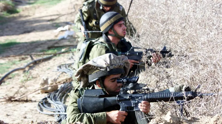 Israeli soldiers fire live ammunition during clashes with Palestinian youths 29 October 2000 at Karni crossing in the Gaza Strip. Israeli tanks opened fire on a Palestinian security building at Karni, injuring at least one Palestinian policeman. AFP PHOTO/Fayez NURELDINE