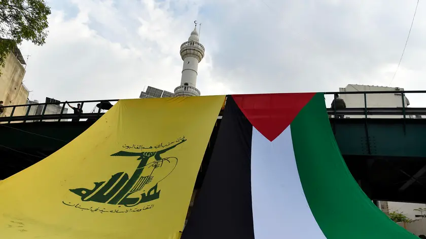 epa10943146 The flags of Hezbollah (L) and Palestine hang off a bridge during a protest in solidarity with Palestinians, in Beirut, Lebanon, 27 October 2023. More than 7,000 Palestinians and at least 1,300 Israelis have been killed, according to the Israel Defense Forces (IDF) and the Palestinian health authority, since Hamas militants launched an attack against Israel from the Gaza Strip on 07 October, and the Israeli operations in Gaza and the West Bank which followed it. EPA/WAEL HAMZEH