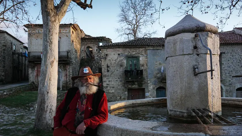 Giuseppe Spagnolo, unico abitante di Roscigno vecchia, fotografato nella piazza del borgo, 3 febbraio 2016. A causa del terreno franoso, il villaggio del Cilento si è gradualmente spopolato negli anni fino a restare disabitato. Ma se i suoi abitanti si sono trasferiti nel paese nuovo, a ripopolarla sono arrivati i turisti che quotidianamente la affollano di passaggio, rapiti dal fascino dei ruderi in pietra, delle stradine scoscese, della piazza ampia, della fontana da cui ancora sgorga acqua. Unico uomo a viverci stabilmente, Giuseppe Spagnolo, dalla barba bianca e la pipa sempre accesa: non si conosce la sua storia, eppure da tempo è divenuto il custode di Roscigno, colui che tra i vicoli del borgo ne racconta la storia a chi ha voglia di ascoltarlo. ANSA/CESARE ABBATE