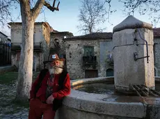 Giuseppe Spagnolo, unico abitante di Roscigno vecchia, fotografato nella piazza del borgo, 3 febbraio 2016. A causa del terreno franoso, il villaggio del Cilento si è gradualmente spopolato negli anni fino a restare disabitato. Ma se i suoi abitanti si sono trasferiti nel paese nuovo, a ripopolarla sono arrivati i turisti che quotidianamente la affollano di passaggio, rapiti dal fascino dei ruderi in pietra, delle stradine scoscese, della piazza ampia, della fontana da cui ancora sgorga acqua. Unico uomo a viverci stabilmente, Giuseppe Spagnolo, dalla barba bianca e la pipa sempre accesa: non si conosce la sua storia, eppure da tempo è divenuto il custode di Roscigno, colui che tra i vicoli del borgo ne racconta la storia a chi ha voglia di ascoltarlo. ANSA/CESARE ABBATE