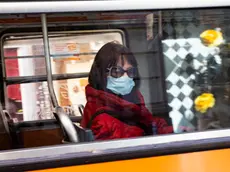 A woman wears a protective face mask aboard of a bus, Milan, Italy, 09 March 2020. ANSA/Marco Ottico