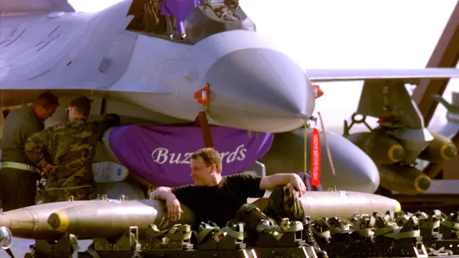 AVI01D:YUGOSLAVIA-KOSOVO-NATO:AVIANO,ITALY,1APR99 - U.S. soldier takes a rest over air bombs while an F16 is repaired behind him at Aviano air base in the North of Italy April 1. Aircrafts from the U.S., Canada, U.K., Spain and Portugal are at Aviano supporting NATO's Operation Allied Force. jr/Photo by Jose Manuel Ribeiro REUTERS