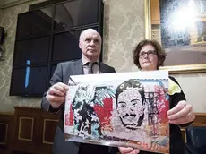 Parents of Giulio Regeni, Claudio (L) and Paola, show the picture of a mural made upon a wall in Berlin, by Egyptians writers, with the image of their son and a stylized cat during a press conference at the Italian Senate, 04 April 2017. Regeni's parents appealed to Pope Francis to bring up the case of the Italian student tortured and murdered in Cairo when he visits Egypt on April 28-29. ANSA/MASSIMO PERCOSSI