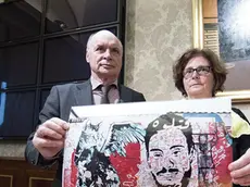 Parents of Giulio Regeni, Claudio (L) and Paola, show the picture of a mural made upon a wall in Berlin, by Egyptians writers, with the image of their son and a stylized cat during a press conference at the Italian Senate, 04 April 2017. Regeni's parents appealed to Pope Francis to bring up the case of the Italian student tortured and murdered in Cairo when he visits Egypt on April 28-29. ANSA/MASSIMO PERCOSSI