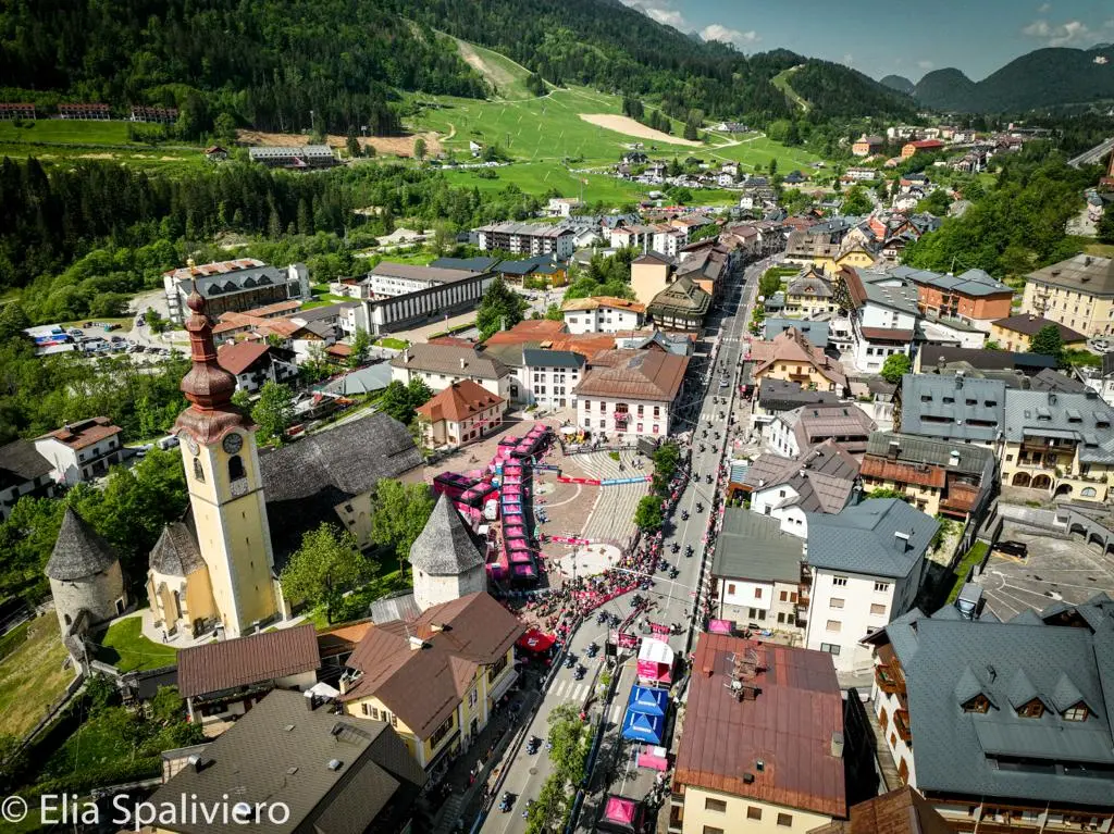 Splende il sole, intanto, in Friuli. Finalmente bel tempo sul Giro inseguito per giorni e giorni dalla pioggia nella sua risalita al Nord; spettacolo fino all’ultimo per una classifica apertissima come non mai. Tantissime le persone sulle strade, a Tarvisio e al Santuario, che applaudono i ciclisti ma soprattutto i due atleti friulani in gara, Alessandro De Marchi e Jonathan Milan, con la sua maglia ciclamino semplicemente passato in 21 tappe da esordiente a eroe acclamato da tutti e protagonista ieri dell’impresa del Giro arrivando in tempo massimo dopo una notte insonne. E poi turisti-tifosi in arrivo da Austria, soprattutto Slovenia per il loro Roglic; telespettatori incollati alle tv da tutto il mondo per assistere al debutto della misteriosa salita del Lussari, musica per le orecchie della Regione (Foto Petrussi)