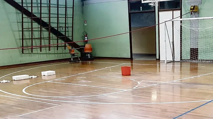 Un secchio per proteggere il parquet dalle infiltrazioni d’acqua dal tetto della palestra