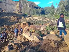 epa11365145 People walk with their belongings in the area where a landslide hit the village of Kaokalam, Enga province, Papua New Guinea, 24 May 2024. A landslide reportedly killed about 100 people in a remote village of northern Papua New Guinea. EPA/NINGA ROLE BEST QUALITY AVAILABLE AUSTRALIA AND NEW ZEALAND OUT EDITORIAL USE ONLY EDITORIAL USE ONLY