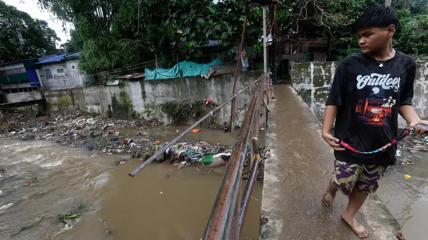 epa11581215 A resident looks over from a damaged bridge in a flood-affected village in Antipolo, Rizal province, about 40 kilometers east of Manila, Philippines, 03 September 2024. According to a 03 September report by the National Disaster Risk Reduction and Management Council (NDRRMC), ten people have died, ten have been injured, and thousands of residents left their homes due to flooding in the wake of Typhoon Yagi. EPA/ROLEX DELA PENA