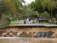 epa11035366 Residents walk near a section of a road that was washed away at the end of Holloways Beach Esplanade in Cairns, Queensland, Australia, 18 December 2023. Residents in far north Queensland are bracing for more rain and further significant flooding. EPA/JOSHUA PRIETO AUSTRALIA AND NEW ZEALAND OUT