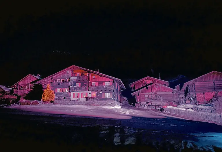 Le case in legno della borgata Kratten illuminate di rosa (Foto Solero)