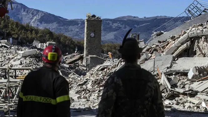 FILE - A firefighter, left, and an alpine soldier look at rubble in the hilltop town of Amatrice after an earthquake with a preliminary magnitude of 6.6 struck central Italy on Oct. 30, 2016. The powerful earthquake rocked the same area of central and southern Italy hit by a quake in August, and a pair of aftershocks just a week prior to this one sent already quake-damaged buildings crumbling after a week of temblors that have left thousands homeless. (Massimo Percossi/ANSA via AP, File)