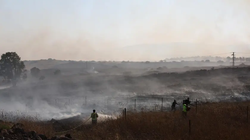 epa11385808 Firefighters work to douse a fire that broke out following projectiles fired from southern Lebanon, near the town of Katzrin in the Golan Heights, next to the Israeli border with Syria, 02 June 2024. The Israeli Army spokesperson reported on 02 June that 15 projectiles were fired from Lebanon toward the area of Katzrin. The projectiles fell in open areas and no injuries were reported. EPA/ATEF SAFADI