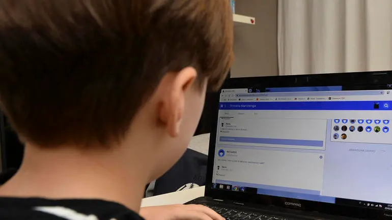 Un giovane studente della Scuola Elementare Renzo Pezzani di Milano svolge alcuni compiti online organizzati dall'insegnante dopo la chiusura delel scuole a causa dell'emergenza coronavirus. Ansa/Andrea Fasani