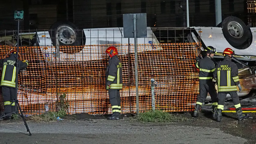 Rescue personnel work at the site where a passenger bus with people on board fell from an elevated section ending up on the railway track that runs alongside the road in Mestre, near Venice, Italy, 03 October 2023. There are at least 21 confirmed deaths and 15 injured. ANSA/ANDREA MEROLA (bus, incidente stradale, cavalcavia, vigili fuoco, generica, pompieri)