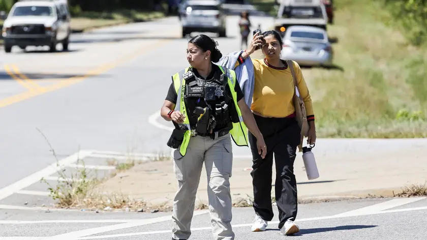 epa11584980 A police officer walks with a woman near the scene of a reported shooting at Apalachee High School in Winder, Georgia, USA, 04 September 2024. The Georgia Bureau of Investigation (GBI) announced on social media platform X, formerly Twitter, that the law enforcement personnel responded with other first responders to a shooting at the school and one suspect was in custody. EPA/ERIK S. LESSER