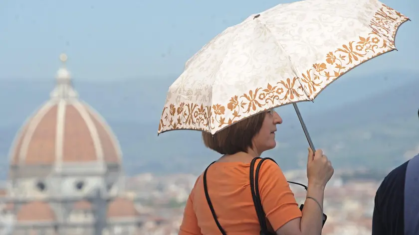 Una turista si ripara dal sole con un ombrellino a Firenze, 28 aprile 2012. Un'Italia di fine aprile assolata e sgombra di nuvole come fosse già estate: questa l'immagine della Penisola vista dal satellite. E' l'azione di 'Hannibal', l'anticiclone africano che sta invadendo tutta l'Europa: Le temperature sono da record: Firenze la regina con 31 gradi. ANSA/ MAURIZIO DEGL'INNOCENTI