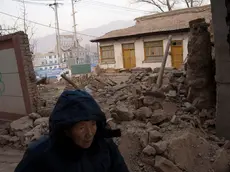 epa11039520 A woman walks past a house damaged by the earthquake in Dahejia, Gansu Province, China, 21 December, 2023. A 6.2 earthquake hit the region on 18 December killing more than 100 people. EPA/ANDRES MARTINEZ CASARES