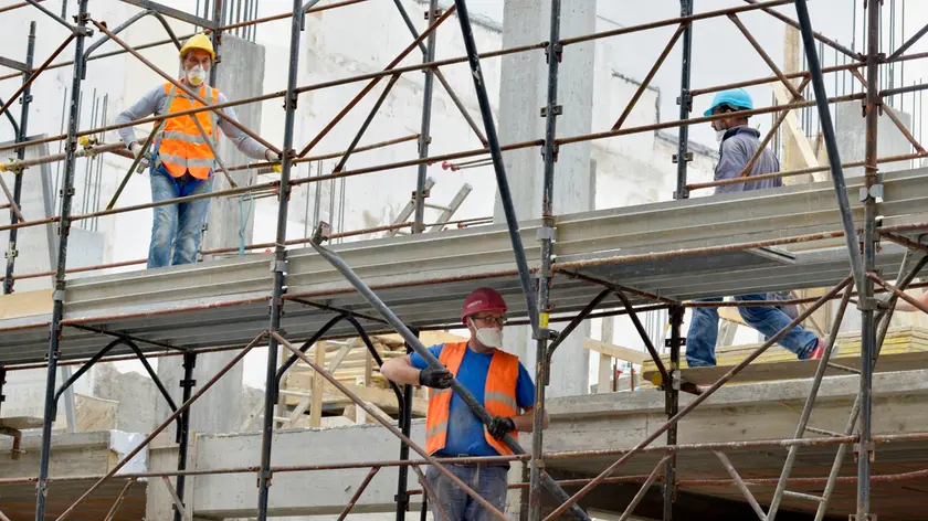 EMERGENZA CORONAVIRUS CORONA VIRUS COVID19 COVID 19.FASE 2 DUE.RIPRENDE L' EDILIZIA.CANTIERE DI EDILIZIA ABITATIVA.CANTIERI EDILI.OPERAIO OPERAI SICUREZZA SUL LAVORO.MASCHERINA PROTETTIVA MASCHERINE PROTETTIVE CASCO PROTETTIVO CASCHI PROTETTIVI ELMETTO ELMETTI.IMPALCATURA IMPALCATURE