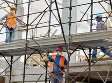 EMERGENZA CORONAVIRUS CORONA VIRUS COVID19 COVID 19.FASE 2 DUE.RIPRENDE L' EDILIZIA.CANTIERE DI EDILIZIA ABITATIVA.CANTIERI EDILI.OPERAIO OPERAI SICUREZZA SUL LAVORO.MASCHERINA PROTETTIVA MASCHERINE PROTETTIVE CASCO PROTETTIVO CASCHI PROTETTIVI ELMETTO ELMETTI.IMPALCATURA IMPALCATURE