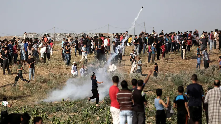 epa06020363 A Palestinian protester throws back an Israeli tear-gas during clashes between Israeli troops and Palestinian protesters near the border, between Israel and The Gaza Strip, in the east Jabalia refugee camp, northern Gaza Strip, 09 June 2017 (issued 10 June 2017). One Palestinian was shot dead by Israeli troops and four others were injured following a protest against the Israeli blockade. EPA/MOHAMMED SABER