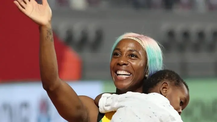 epa07880969 Shelly-Ann Fraser-Pryce of Jamaica celebrates with her son Zyon after winning the women's 100m final during the IAAF World Athletics Championships 2019 at the Khalifa Stadium in Doha, Qatar, 29 September 2019. EPA/YAYHA ARHAB