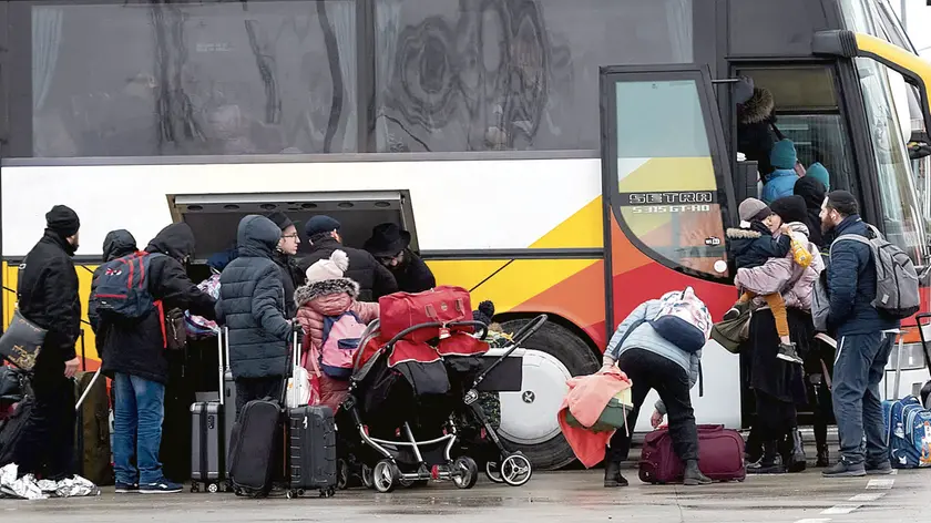 Refugees fleeing war in Ukraine board a bus as they arrive to Palanca, Moldova, Tuesday, March 1, 2022. (AP Photo/Aurel Obreja)