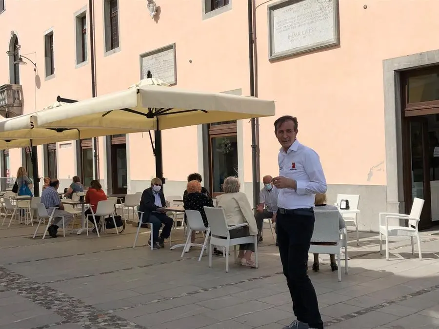 Avventori e un cameriere all'esterno di un bar a Palmanova