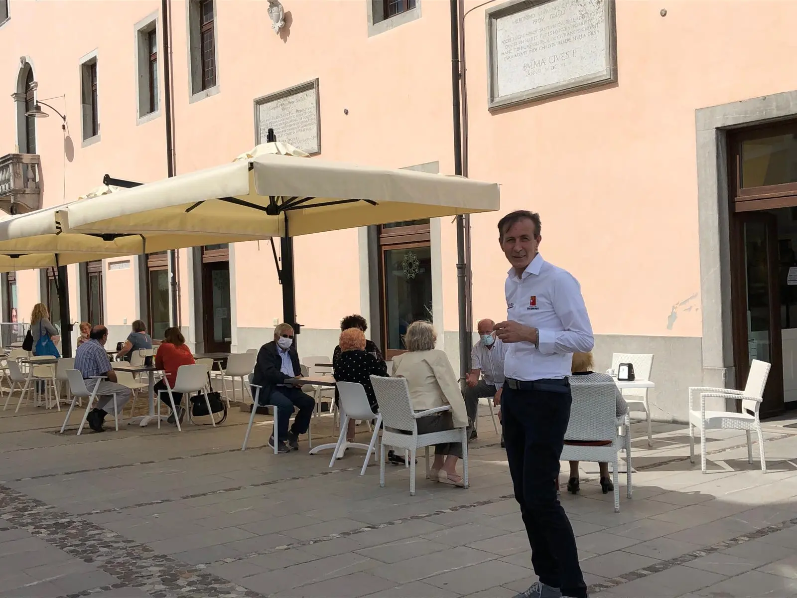 Avventori e un cameriere all'esterno di un bar a Palmanova