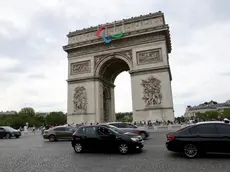 epa11496584 Cars pass in front of the Arc de Triomphe which is decorated with the colors of the Paralympic Games ahead of the opening ceremony of the Paris 2024 Olympic Games, in Paris, France, 25 July 2024. The opening ceremony of the Paris 2024 Olympic Games will begin on 26 July with a nautical parade on the Seine river and end on the protocol stage in front of the Eiffel Tower. EPA/ALI HAIDER