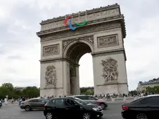 epa11496584 Cars pass in front of the Arc de Triomphe which is decorated with the colors of the Paralympic Games ahead of the opening ceremony of the Paris 2024 Olympic Games, in Paris, France, 25 July 2024. The opening ceremony of the Paris 2024 Olympic Games will begin on 26 July with a nautical parade on the Seine river and end on the protocol stage in front of the Eiffel Tower. EPA/ALI HAIDER