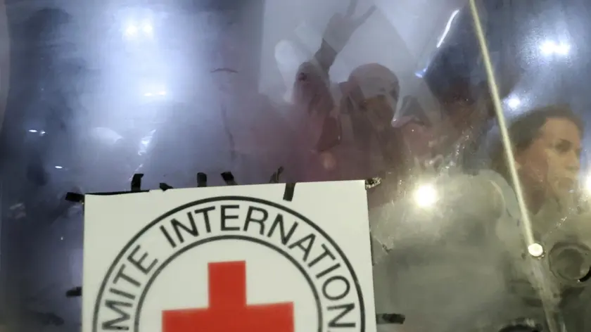 epa10993324 A staff member of the ICRC (International Committe of the Red Cross) looks on, as recently freed Palestinian prisoners celebrate after leaving the Isareli Ofer military prison, in the town of Beitonia near Ramallah, West Bank, 24 November 2023. Israel and Hamas agreed to a four-day ceasefire, mediated by Qatar, the US, and Egypt, that came into effect at 05:00 AM GMT on 24 November, with 50 Israeli hostages, women and children, to be released by Hamas. 150 Palestinian women and children that were detained in Israeli prisons are to be released in exchange. More than 14,000 Palestinians and at least 1,200 Israelis have been killed, according to the Gaza Government media office and the Israel Defense Forces (IDF), since Hamas militants launched an attack against Israel from the Gaza Strip on 07 October, and the Israeli operations in Gaza and the West Bank which followed it. EPA/ALAA BADARNEH