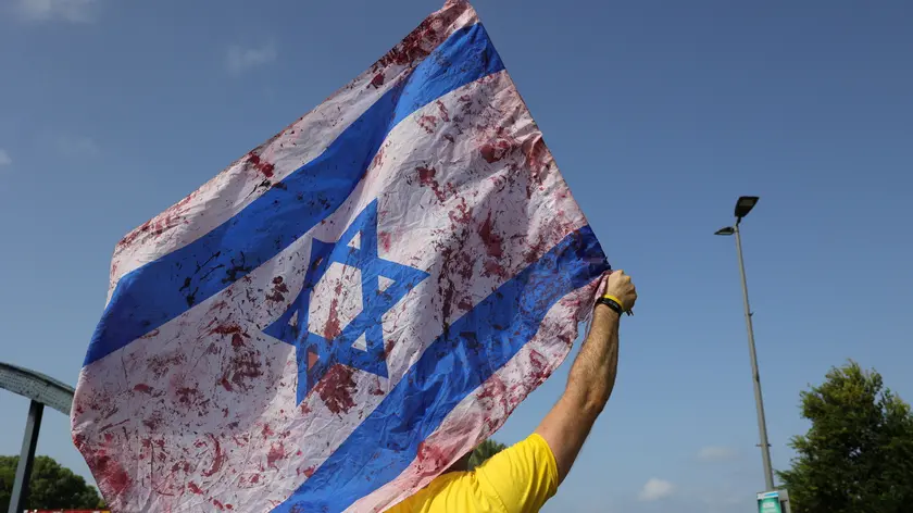 epaselect epa11601461 A demonstrator holds a stained Israeli flag as families of Israeli hostages held by Hamas in Gaza and their supporters block Namir main road during a protest calling for a ceasefire and for the release of the Israeli hostages, in Tel Aviv, Israel, 13 September 2024. According to the Israeli military, 101 Israeli hostages remain in captivity in the Gaza Strip, including the bodies of at least 33 confirmed dead by the IDF. Rallies in Israel have been critical of the Israeli government's handling of the crisis, demanding the immediate release of all hostages. EPA/ABIR SULTAN