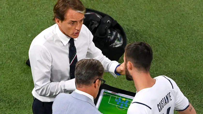 Italy's manager Roberto Mancini gestures as he talks to substitute Bryan Cristante, right, as he prepares to join the game during the Euro 2020 soccer championship quarterfinal match between Belgium and Italy at the Allianz Arena in Munich, Germany, Friday, July 2, 2021. (Stuart Franklin/Pool Photo via AP)