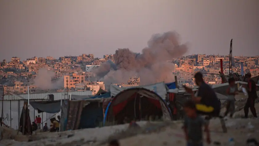 epaselect epa11547886 Smoke rises following an Israeli air strike as internally displaced Palestinians sit next to their tents in Khan Younis camp, southern Gaza Strip, 13 August 2024. More than 39,900 Palestinians and over 1,400 Israelis have been killed, according to the Palestinian Health Ministry and the Israel Defense Forces (IDF), since Hamas militants launched an attack against Israel from the Gaza Strip on 07 October 2023, and the Israeli operations in Gaza and the West Bank which followed it. EPA/HAITHAM IMAD