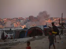epaselect epa11547886 Smoke rises following an Israeli air strike as internally displaced Palestinians sit next to their tents in Khan Younis camp, southern Gaza Strip, 13 August 2024. More than 39,900 Palestinians and over 1,400 Israelis have been killed, according to the Palestinian Health Ministry and the Israel Defense Forces (IDF), since Hamas militants launched an attack against Israel from the Gaza Strip on 07 October 2023, and the Israeli operations in Gaza and the West Bank which followed it. EPA/HAITHAM IMAD