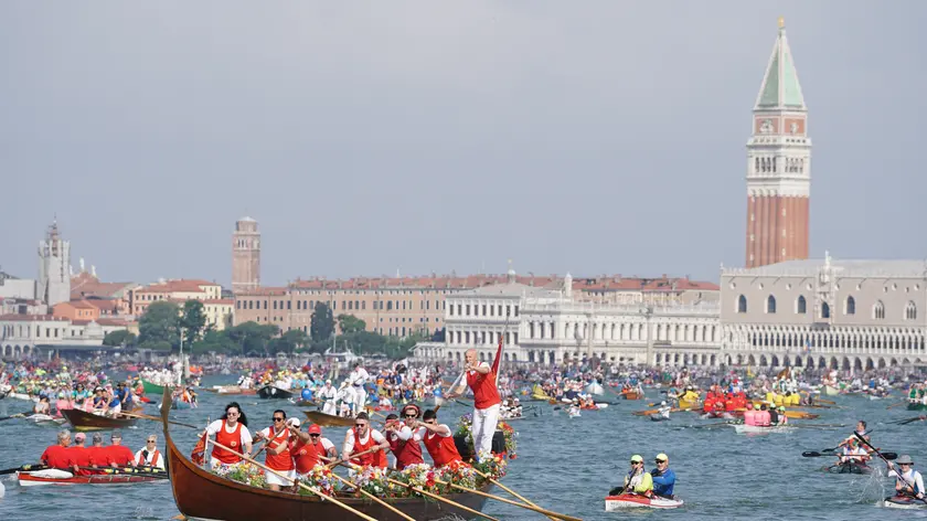 Un gondolone a dieci remi, imbarcazione tipica veneziana, si apre la strada tra i cajak, nello specchio d’acqua di San Marco, alla partenza della 48° edizione della Vogalonga, maratona remiera non competitiva che corre per 32 km nella laguna veneziana, Venezia 19 maggio 2024. ANSA/ANDREA MEROLA